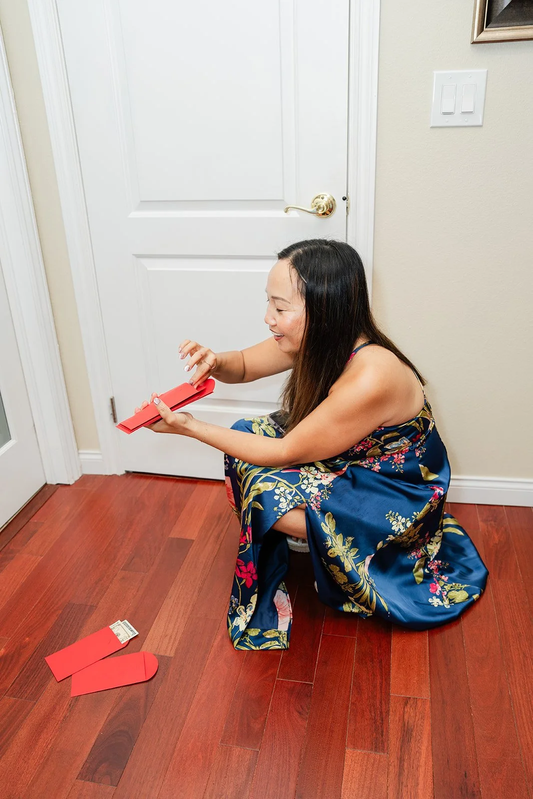 A bridesmaid in blue collecting red envelopes at the door.