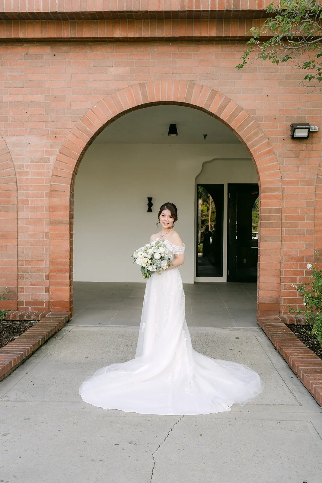Sochi in her white gown framed by a brick archway at Sierra La Verne