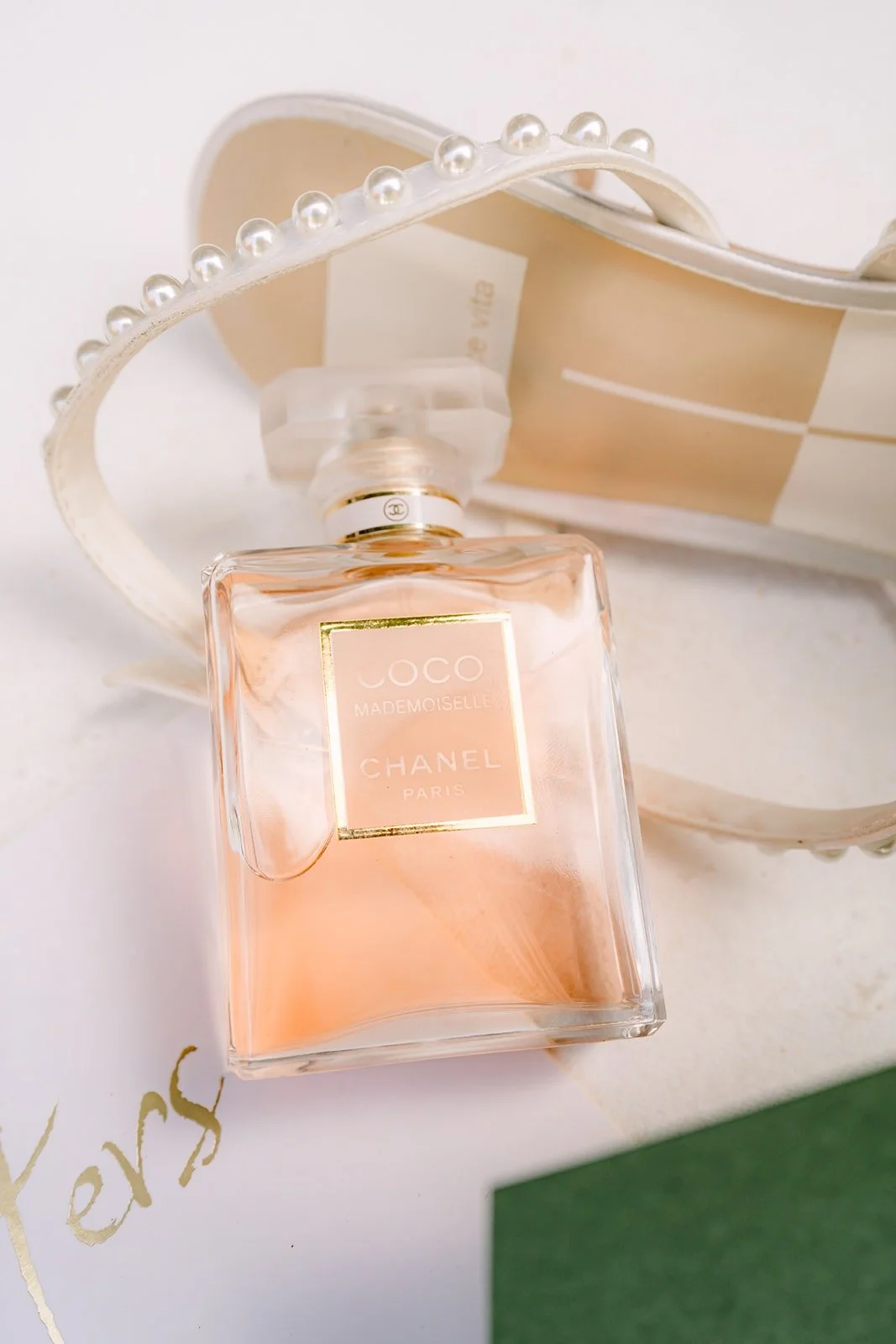 A bottle of perfume styled with the ring box on a white flatlay