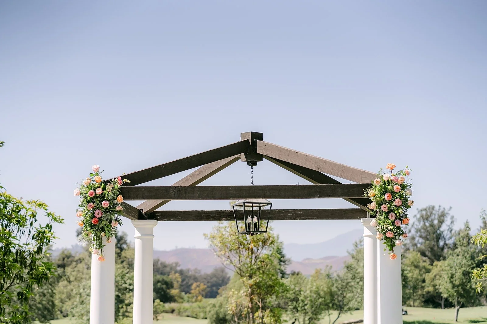 Peach and pink florals hanging from the corners of the wooden pagoda