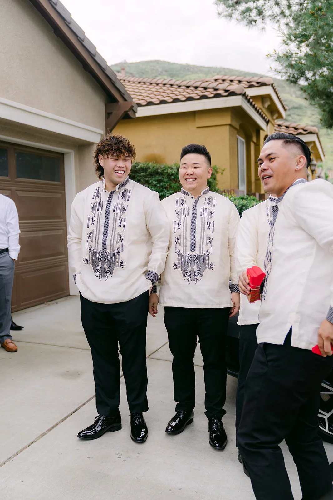 The groom and groomsmen in barong shirts waiting on the driveway before the door game.