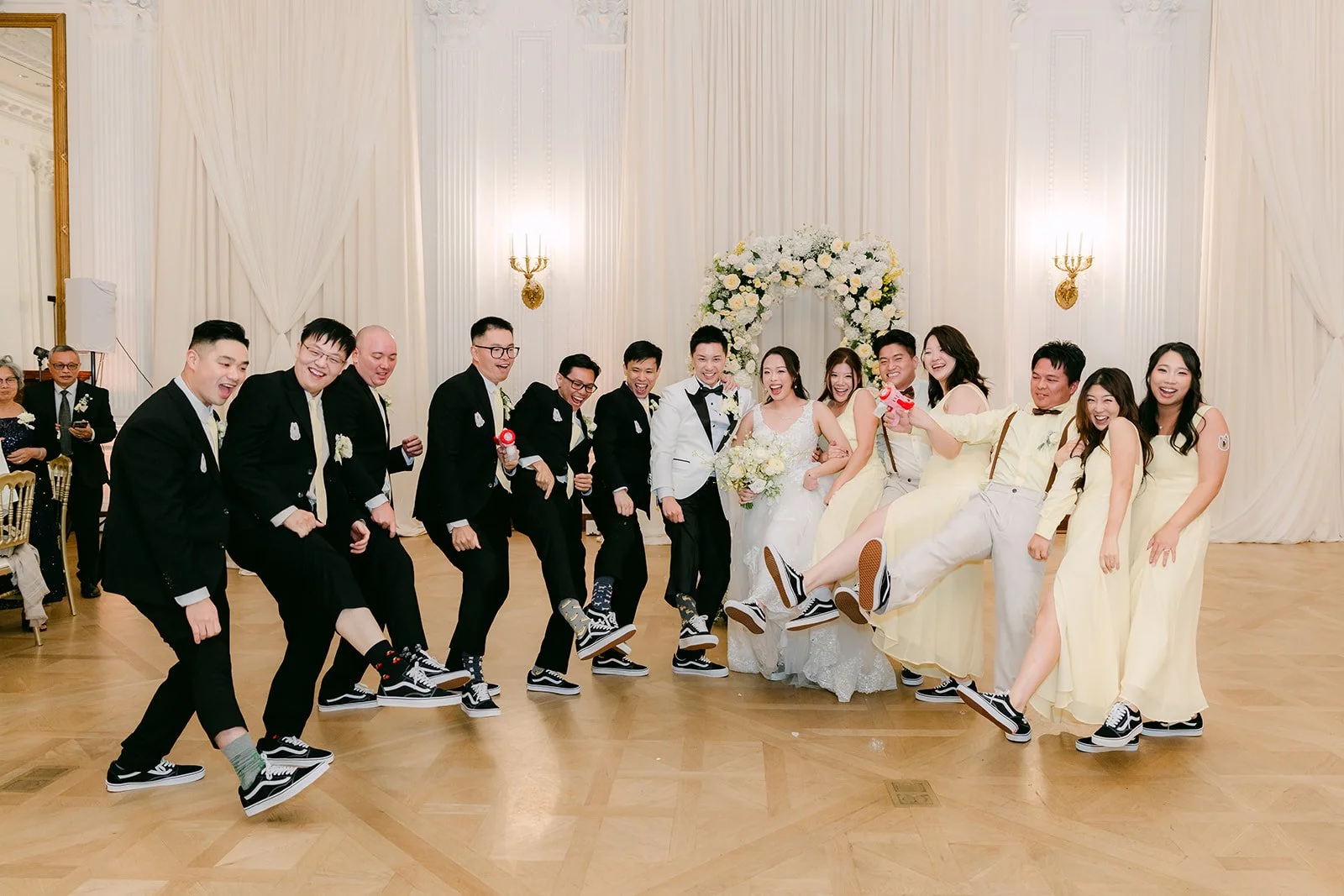 The wedding party hitting a dance move together across the floor.