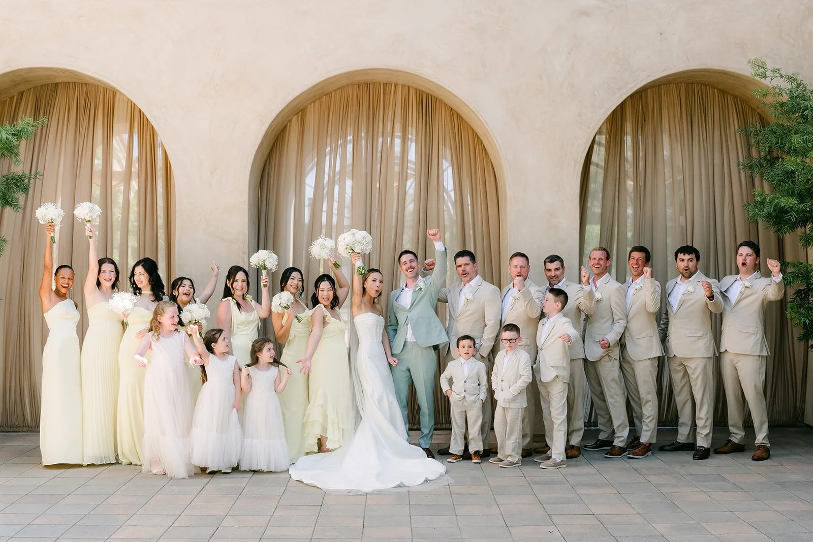 Wedding party with the ring bearers and flower girls in front of the curtained arches