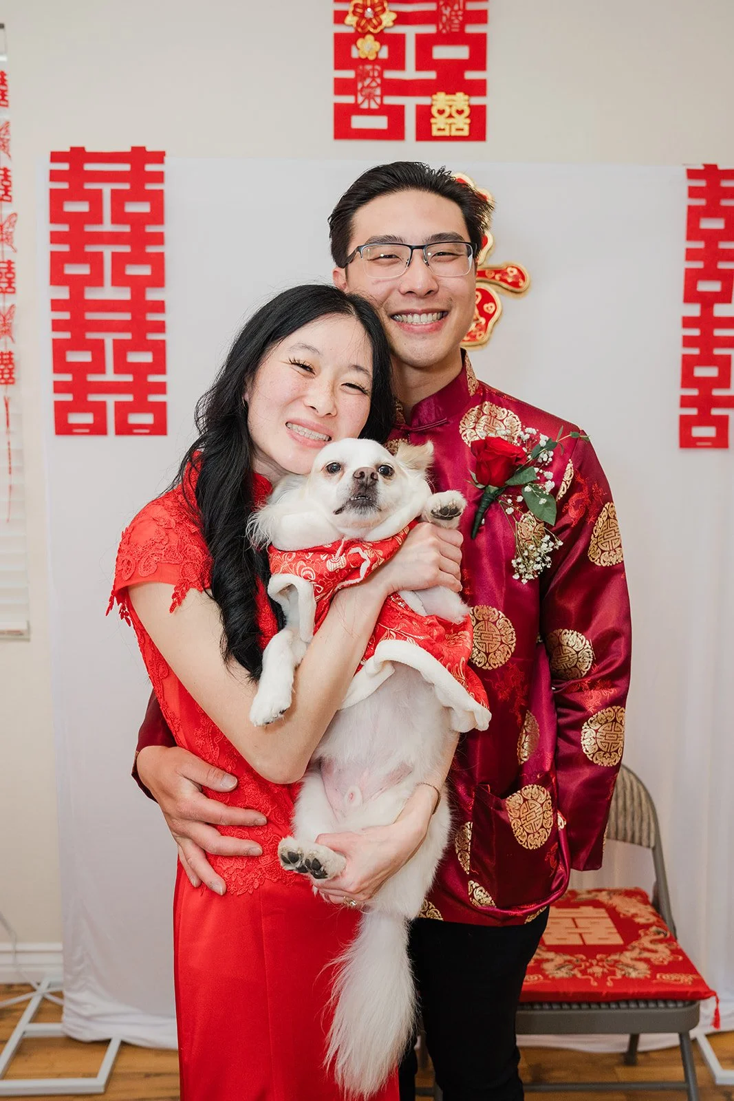 Valerie and Danny under double happiness papercuts with a dog.