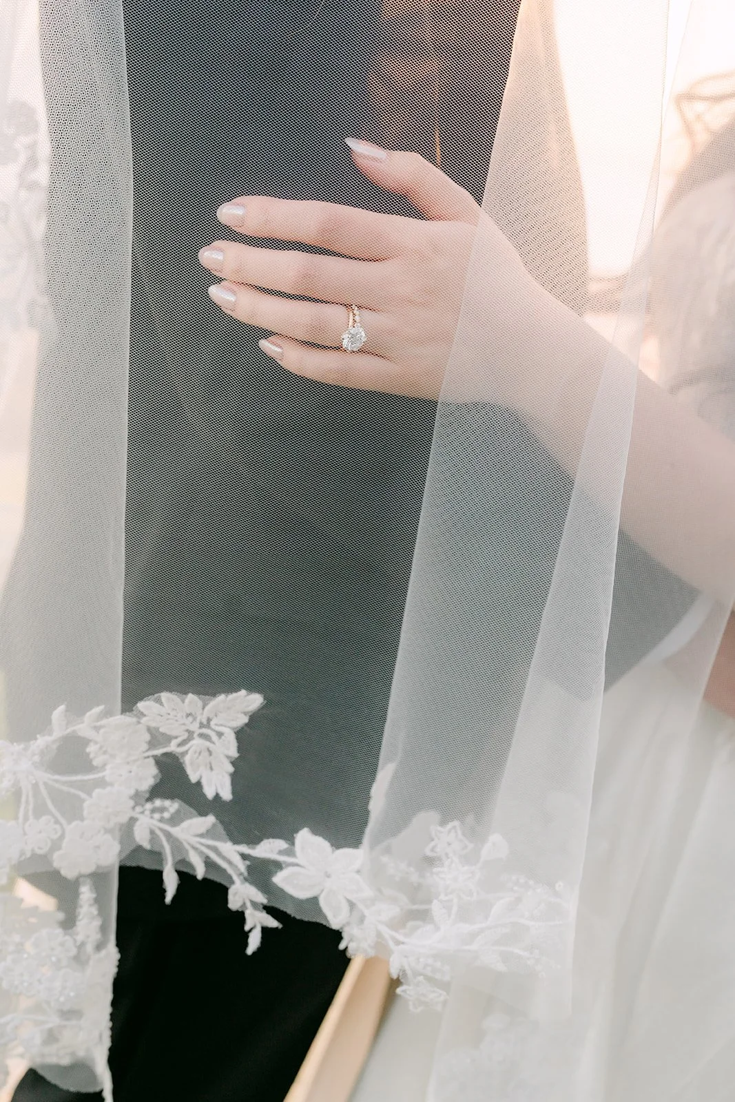 Bride's hand on the groom's lapel through her lace-edged veil