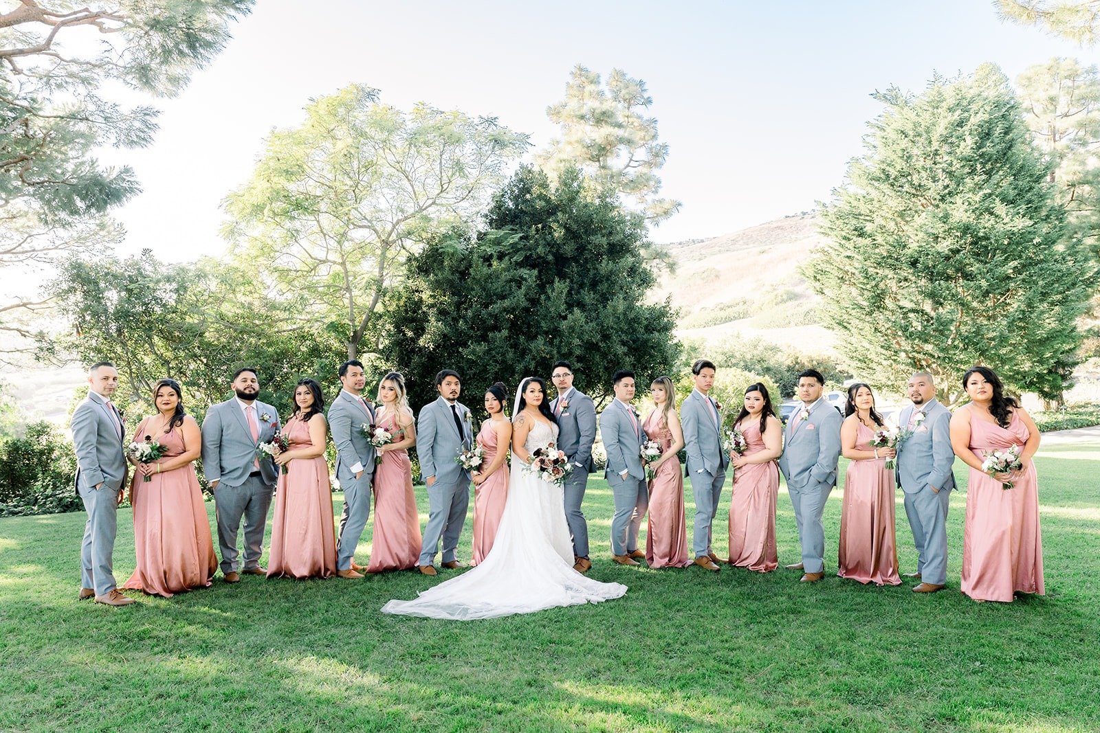 Bridesmaids in dusty rose and groomsmen in grey on the lawn with Betsy and Mikey