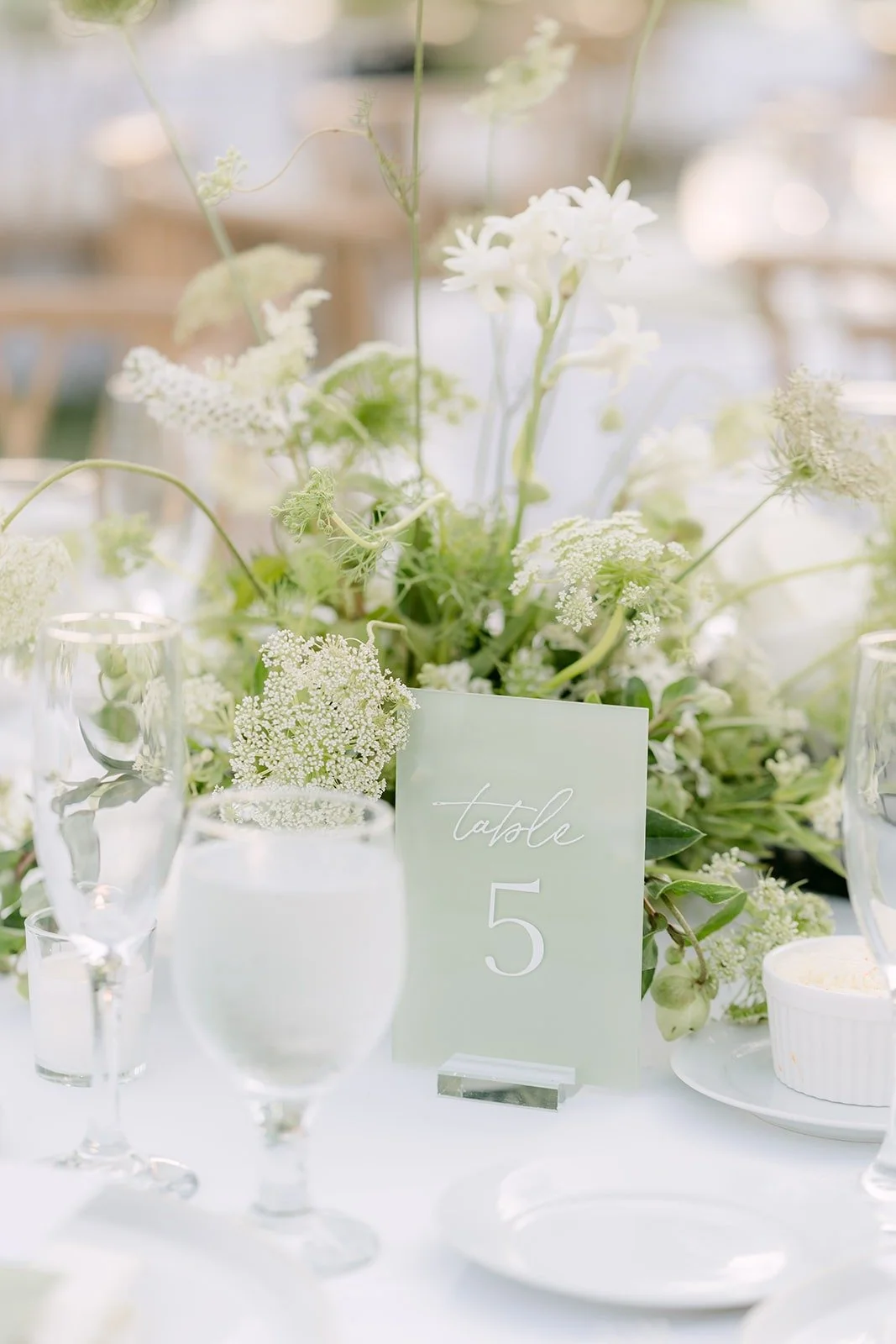 Sage green table number among white florals