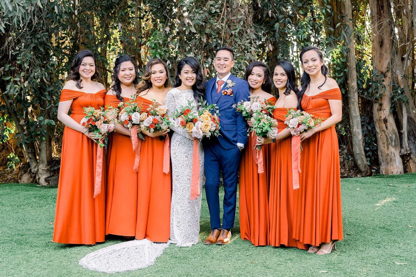 The full wedding party in burnt orange and navy on the lawn at Twin Oaks