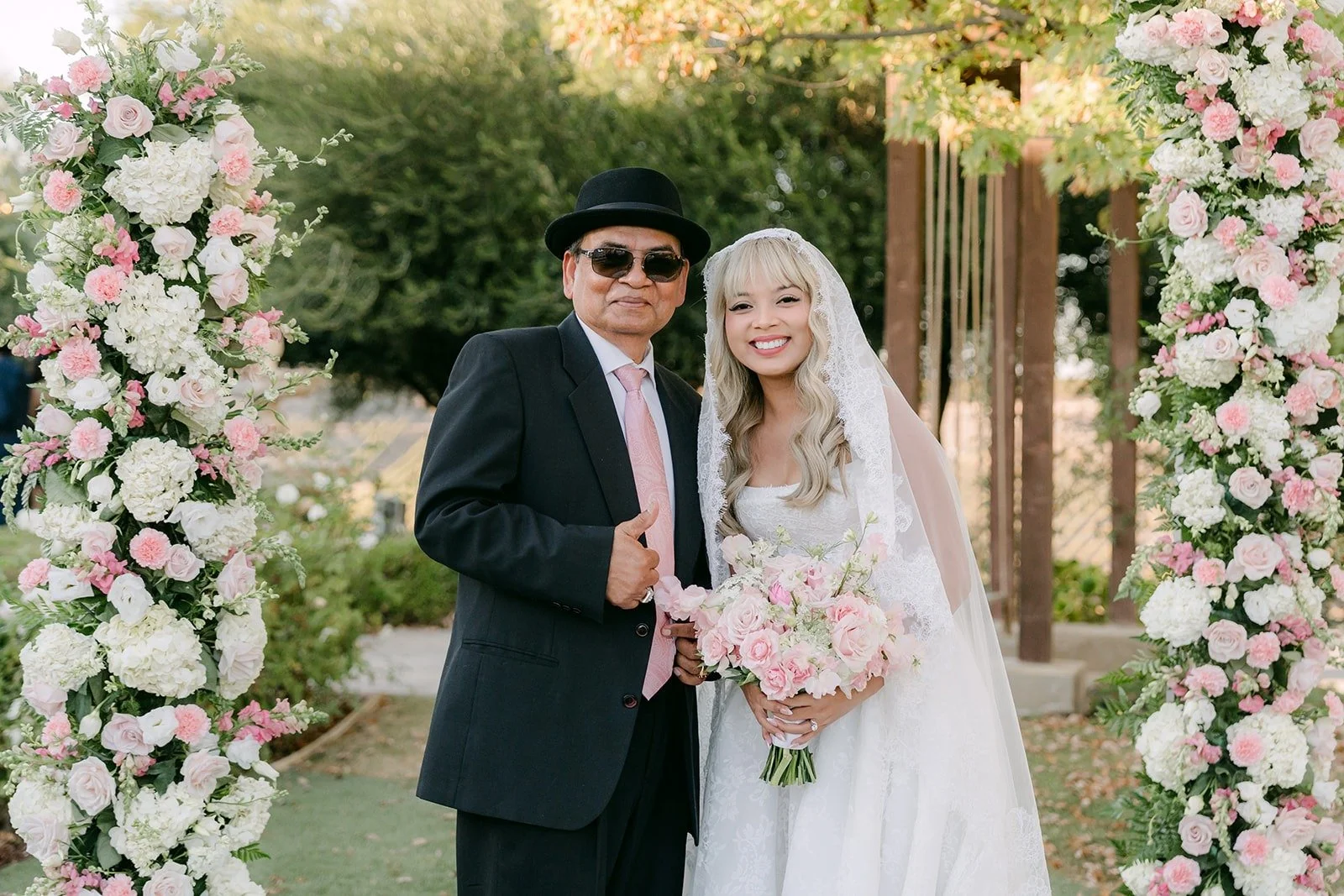 Konitha with a family member in front of the floral arch