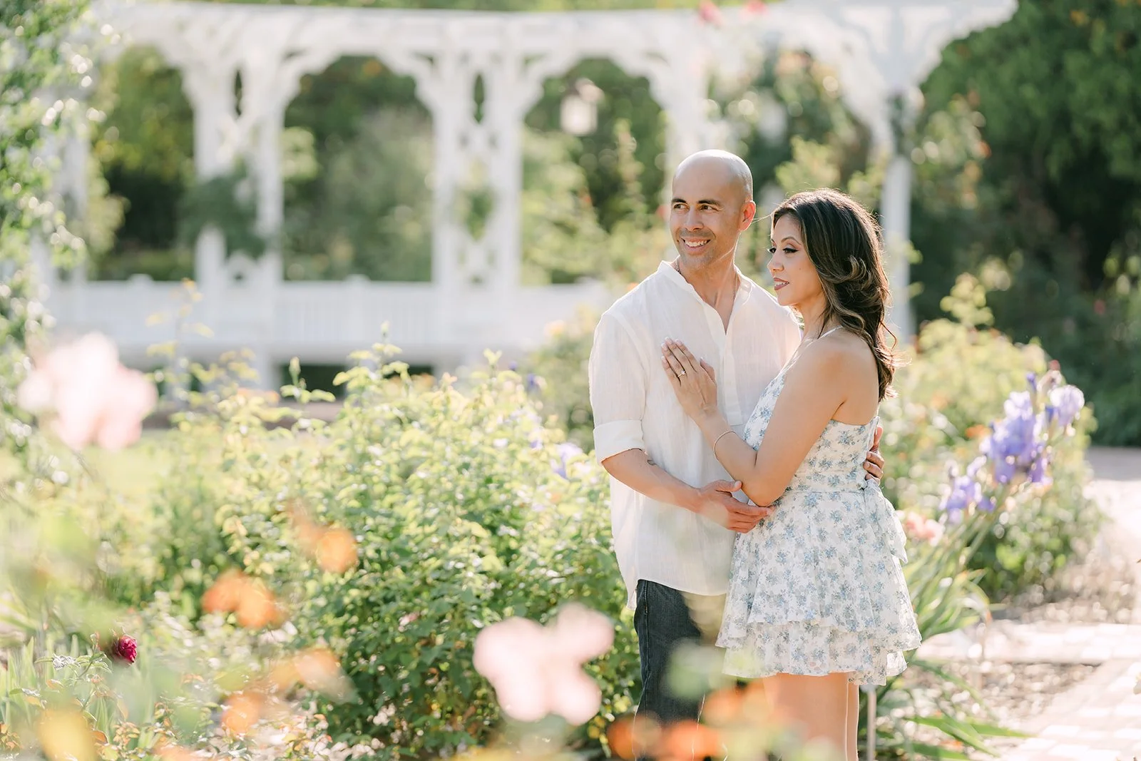 Francesca and Daniel pose in front of the white pergola in the rose garden.