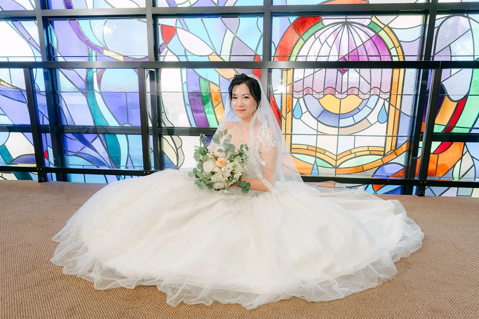 Eunice sits with her gown spread out in front of the stained glass