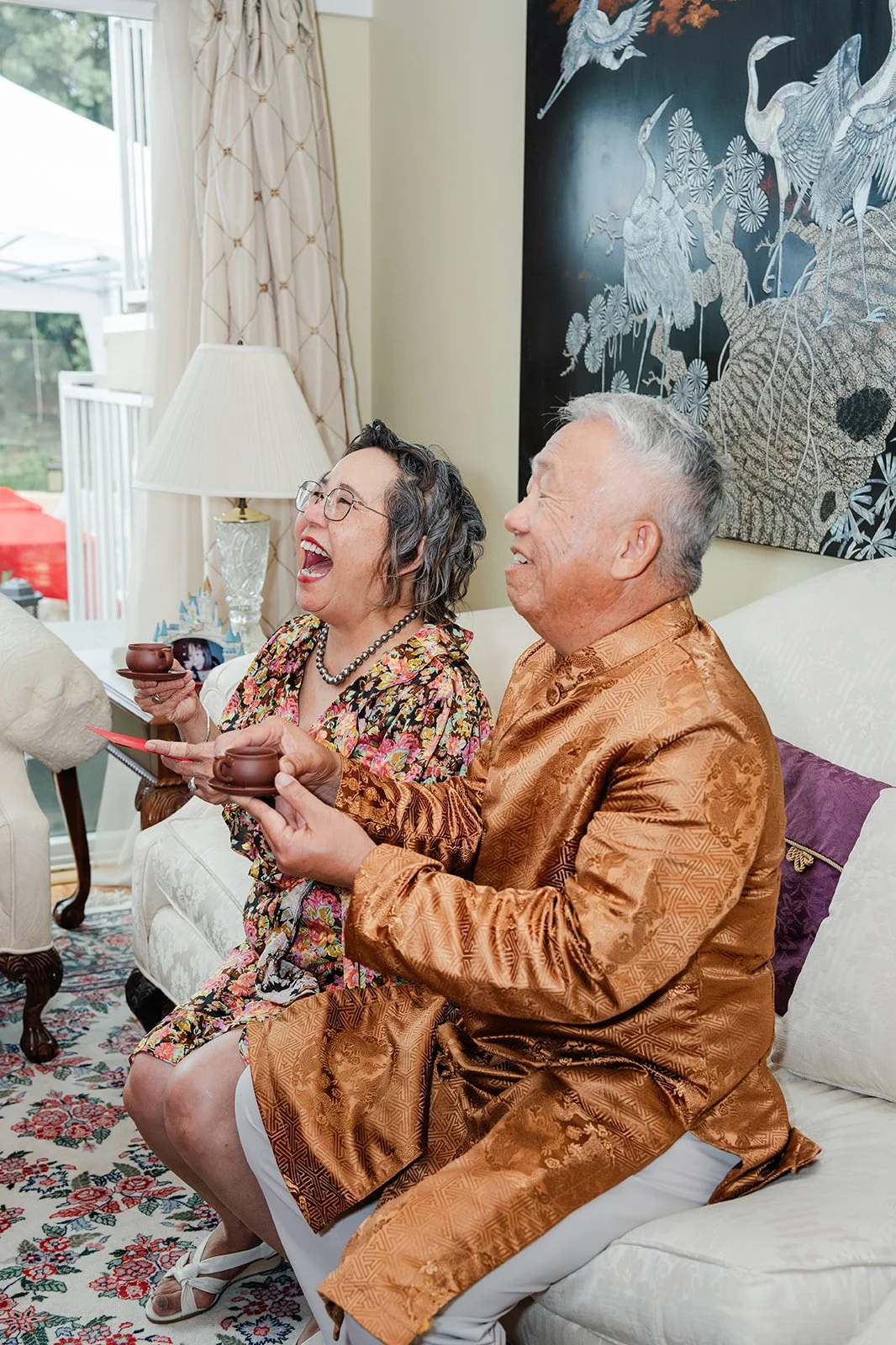 Bridgette and Henrik serving tea to an elder in a gold jacket.