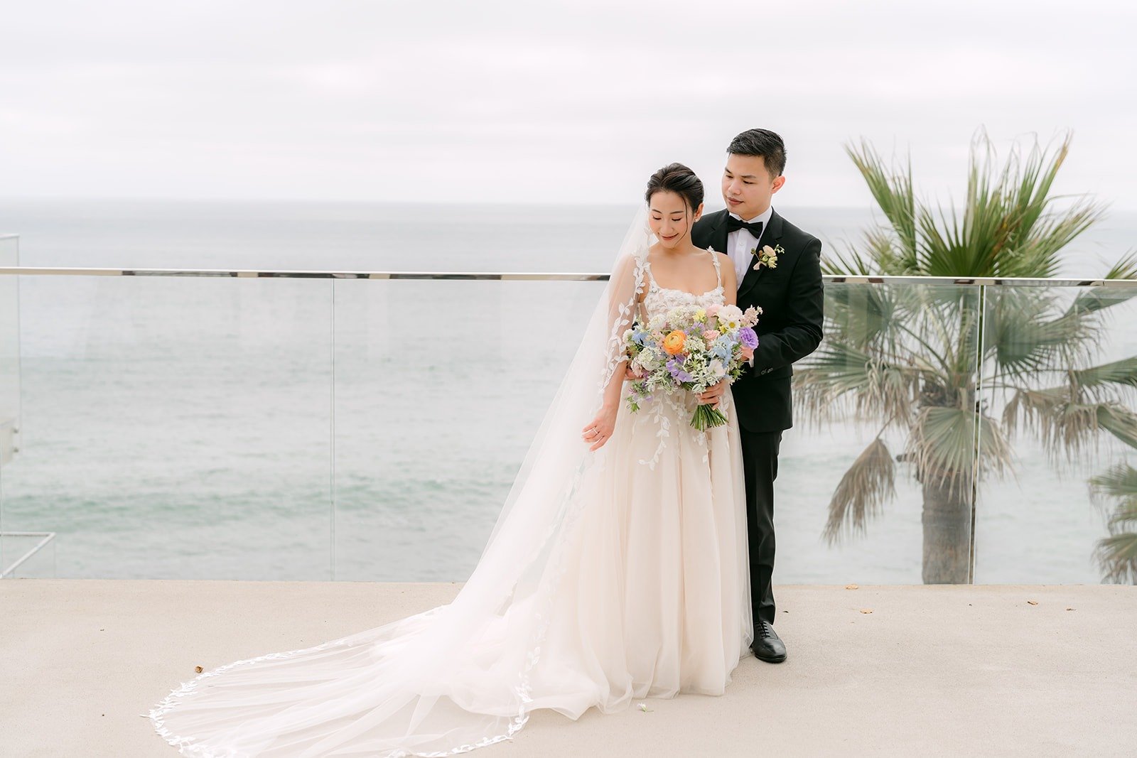 Kylie and Mario on the oceanfront terrace with the Pacific and a palm tree behind them