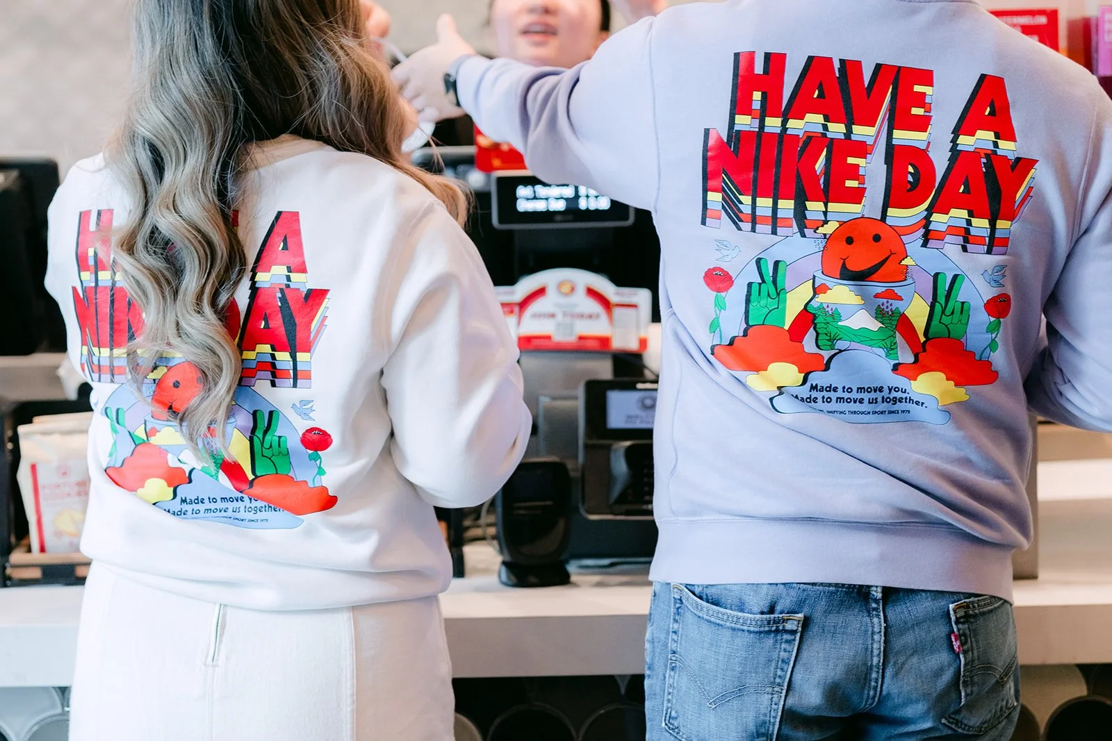 Linh and Ankush at the counter in matching Have a Nice Day sweatshirts.