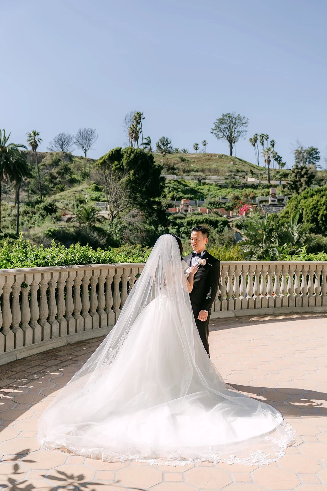 Kelley and Kai's first look with her cathedral veil spread across the terrace