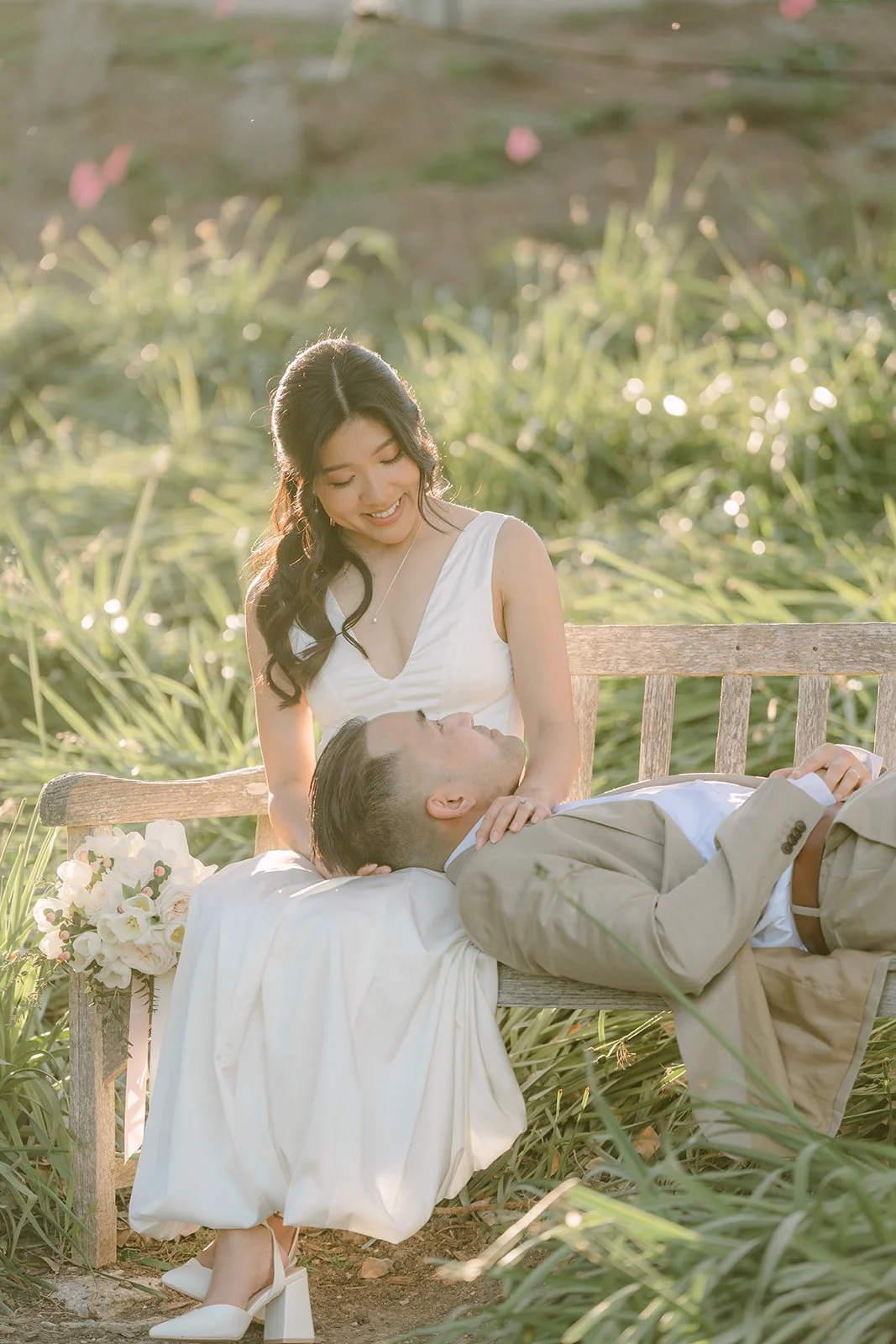 Kim seated on a bench with Vincent resting his head in her lap.