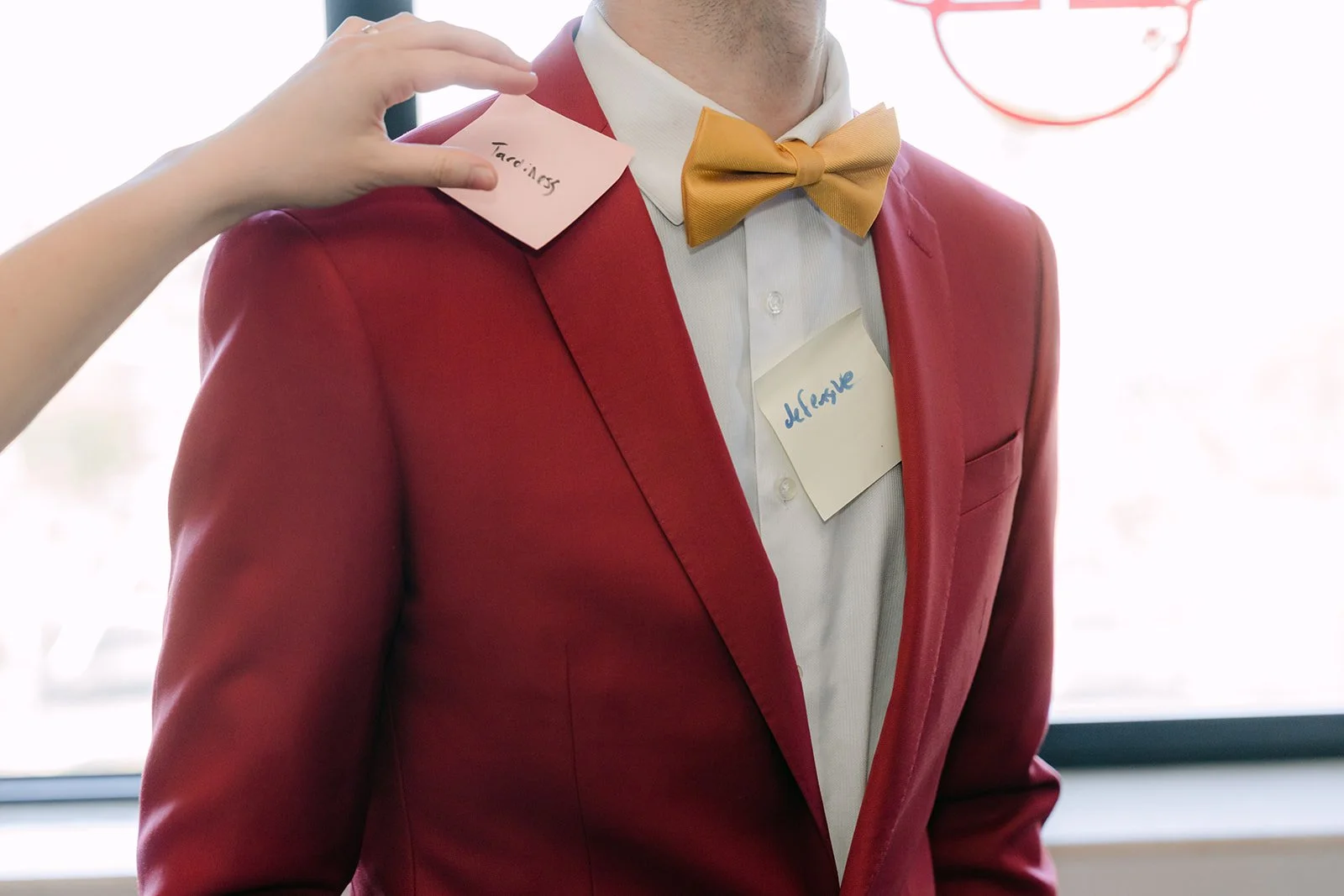 A bridesmaid adjusts Christian's yellow bow tie as part of the door game.