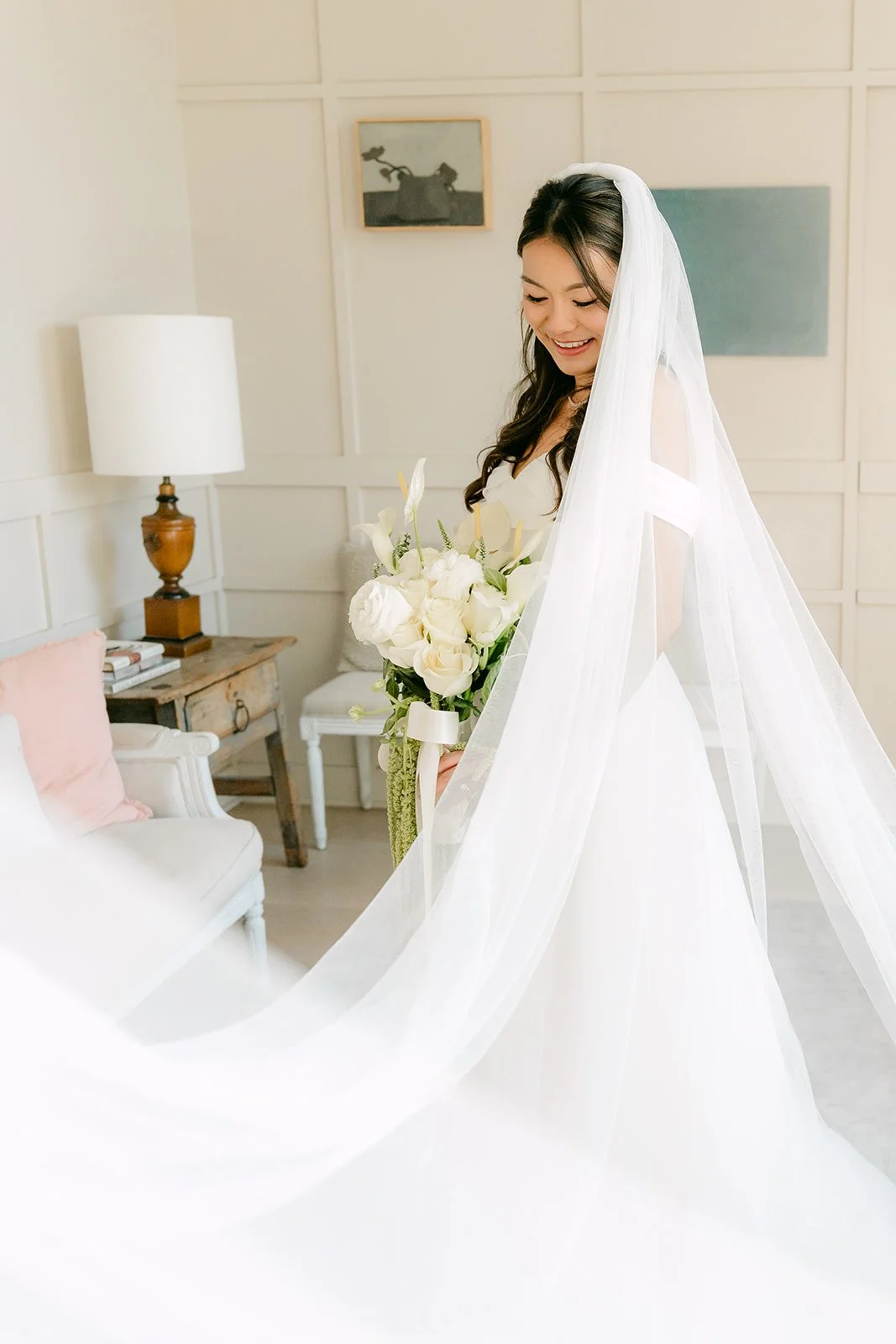Jadee holding a white bouquet under her veil in the bridal suite