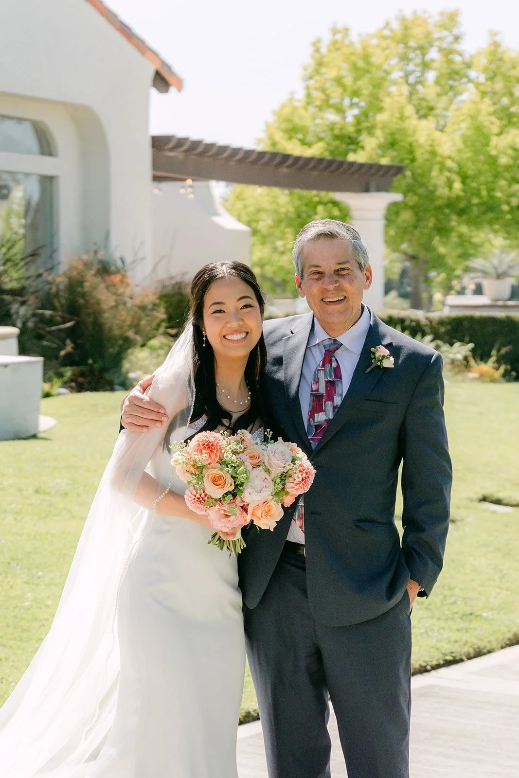 Stephanie and a family member in a gray suit posing with her bouquet