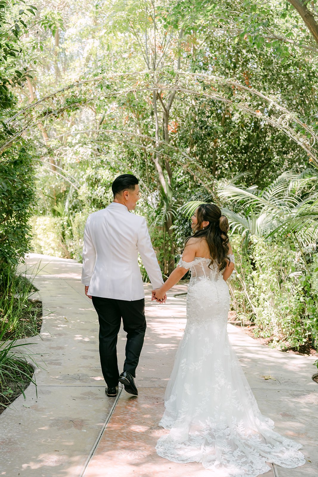 Caryl and Nicole walking hand in hand down a garden path at Eden Gardens.