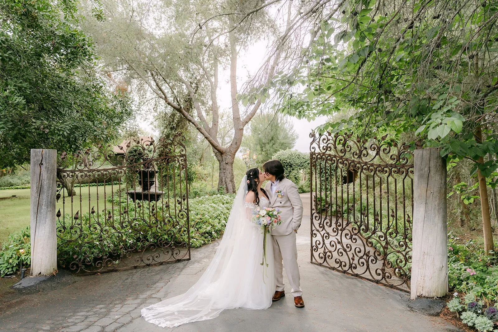 Kat and Mike kissing in front of the open garden gates