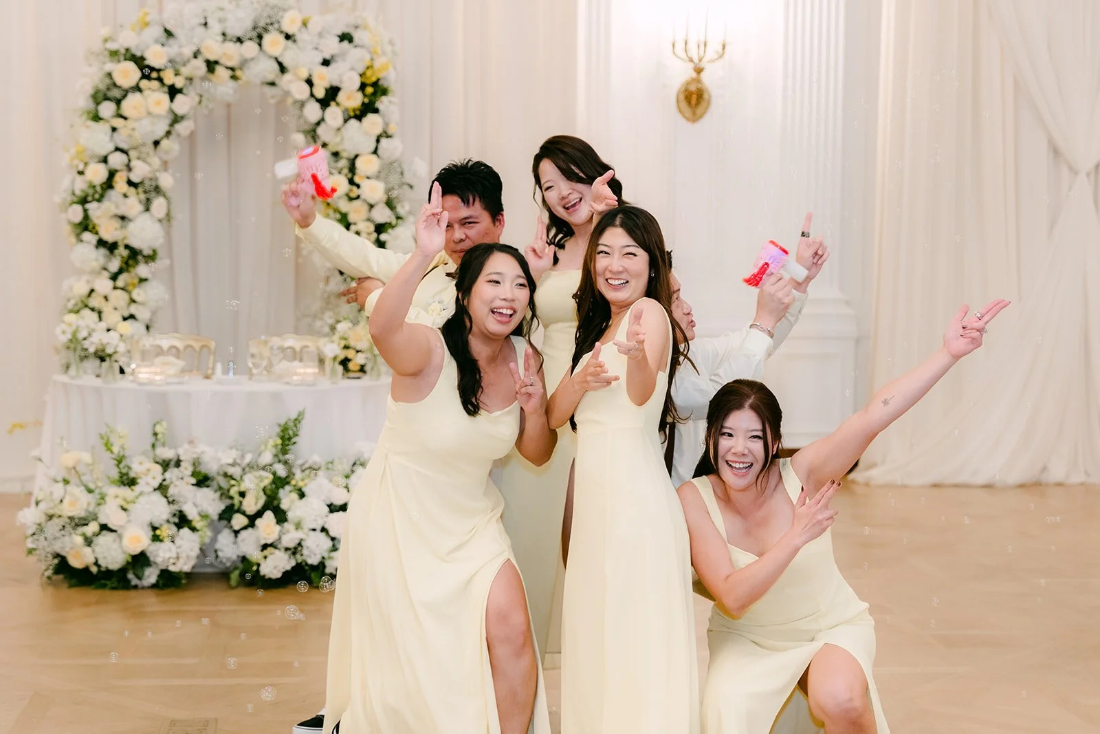 Bridesmaids posing at the floral arch in their Vans sneakers.