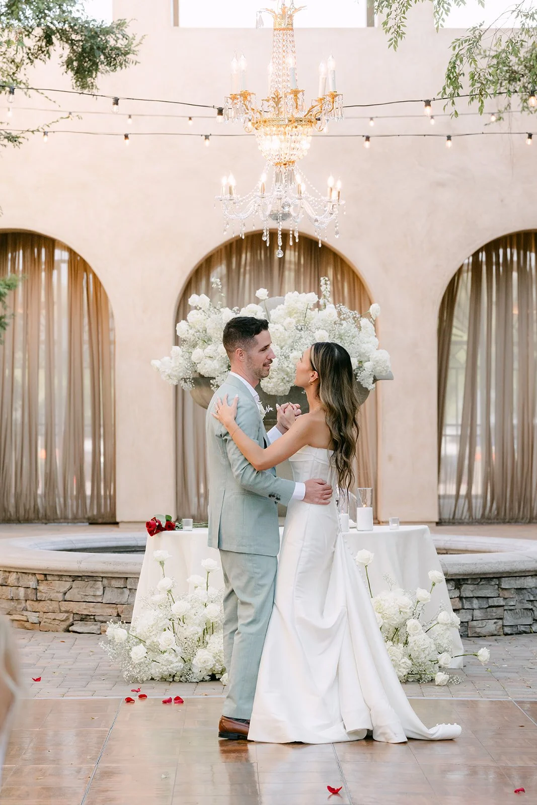 Bride and groom sharing their first dance under the chandelier