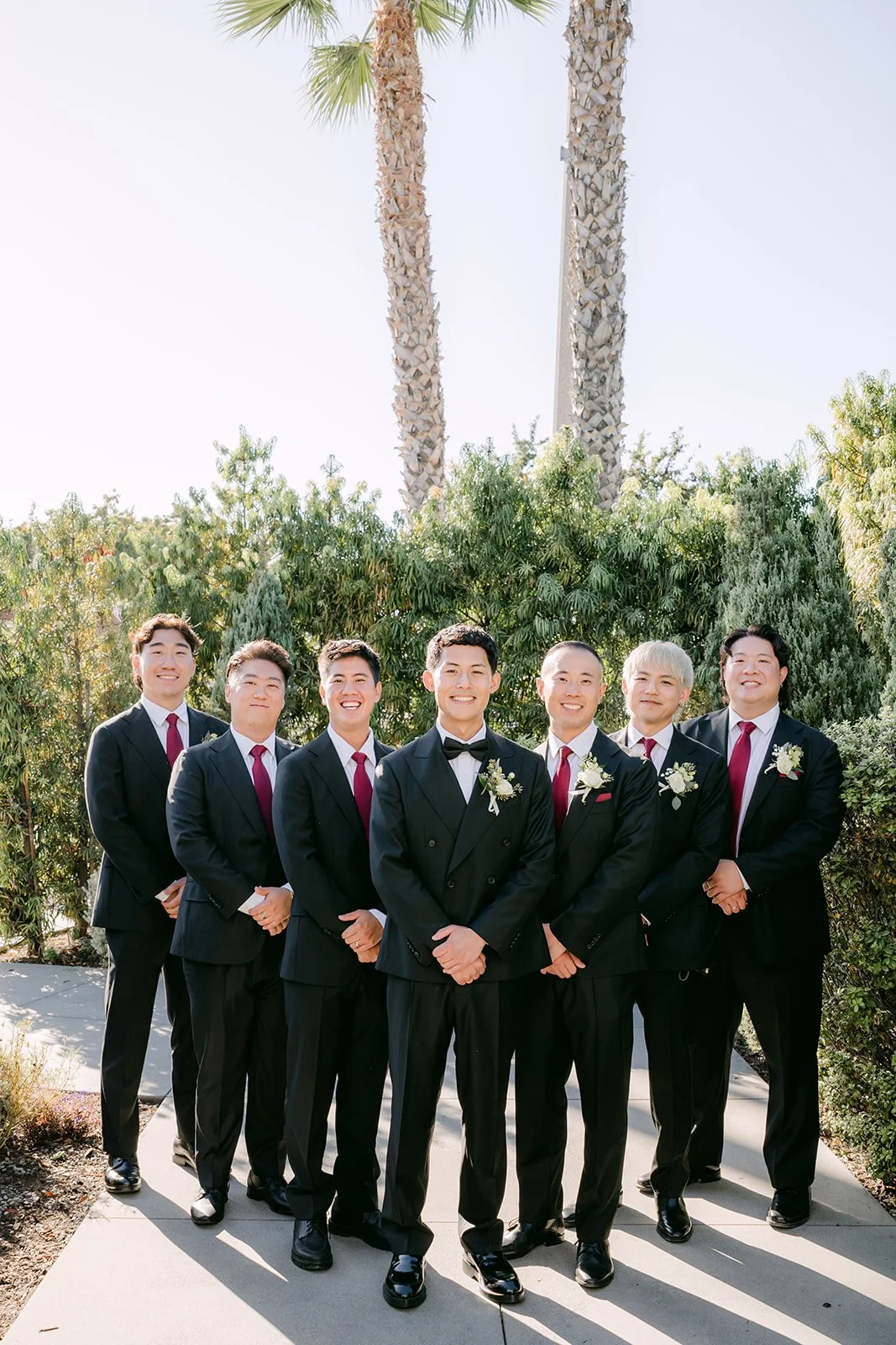 Groomsmen lined up under the palm trees outside The Harper