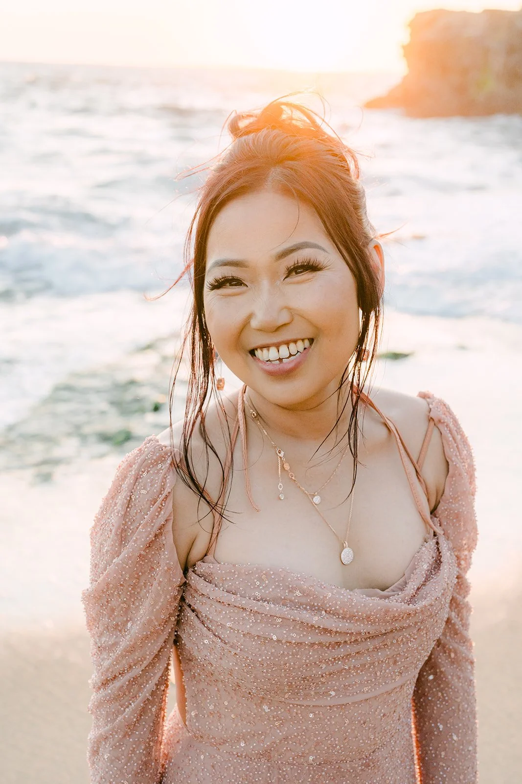 Amy laughing in her pink gown by the ocean.