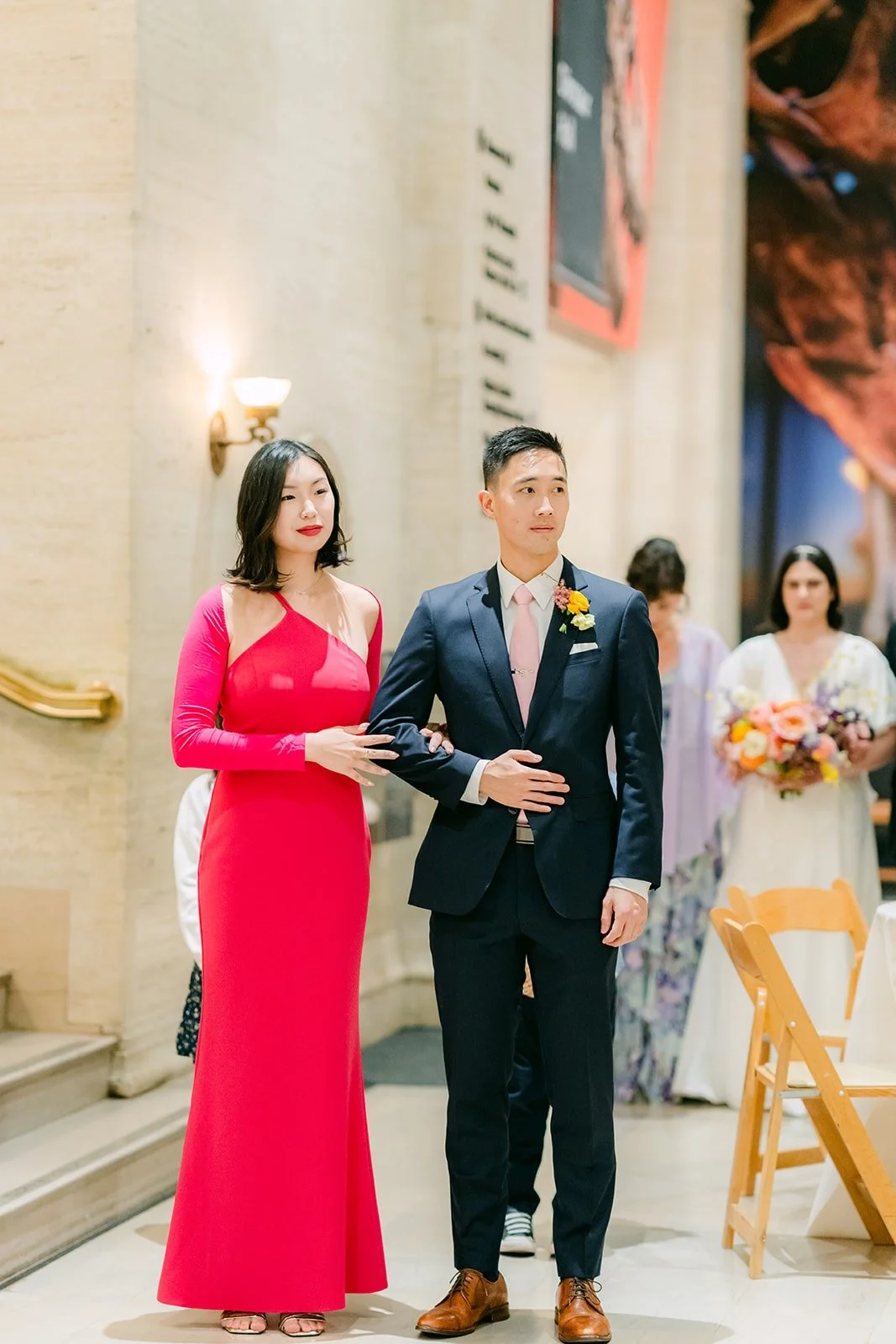 A bridesmaid in red and a groomsman walking down the aisle