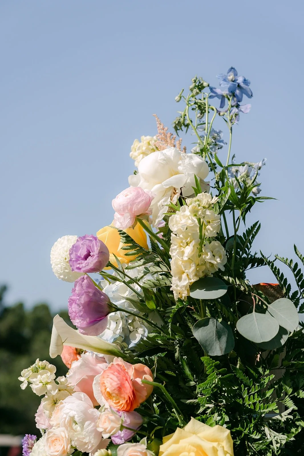 Pastel roses and hydrangeas on a floral column against the blue sky