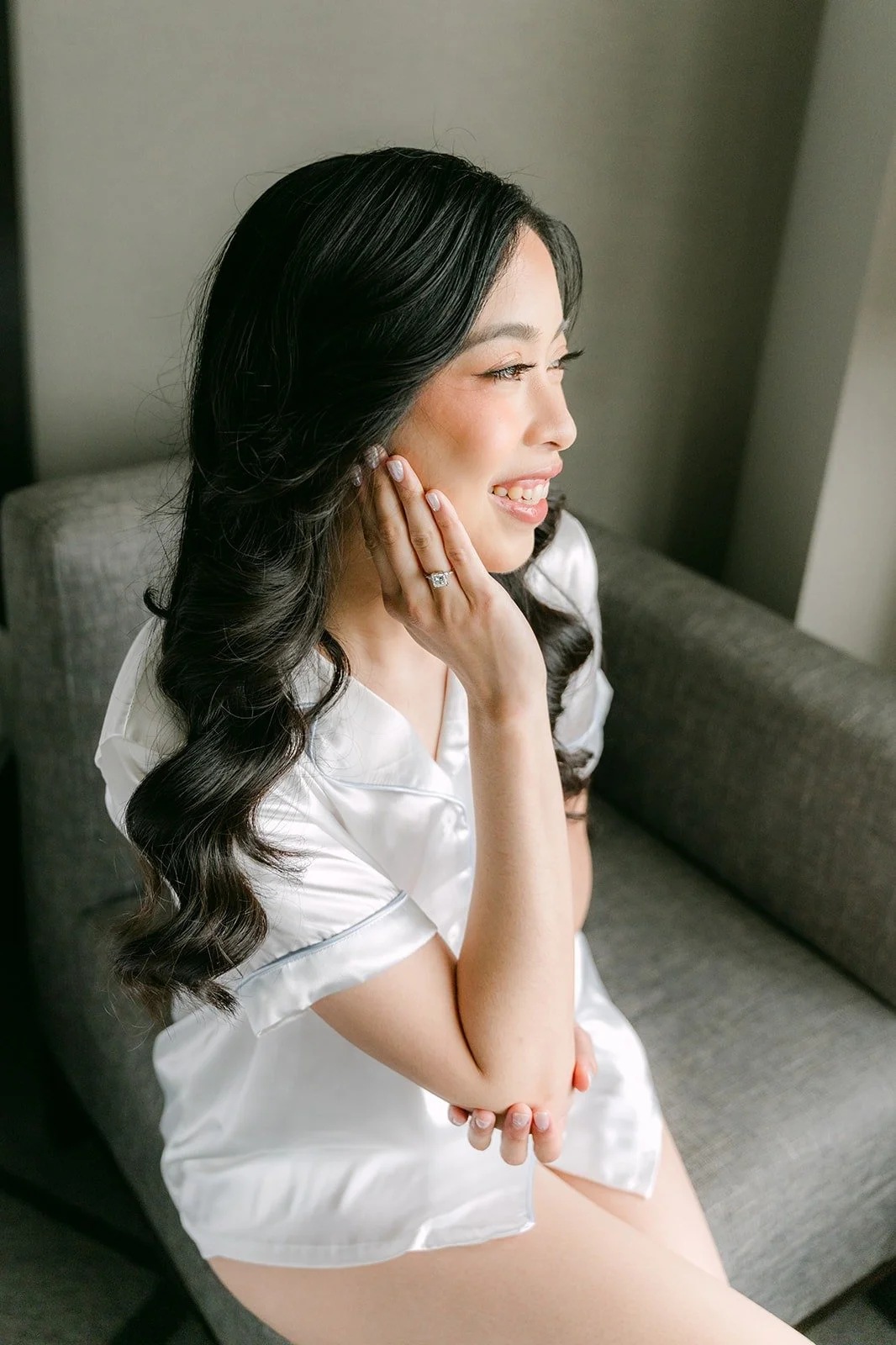 Natalie in a white robe smiling by the window in her hotel room