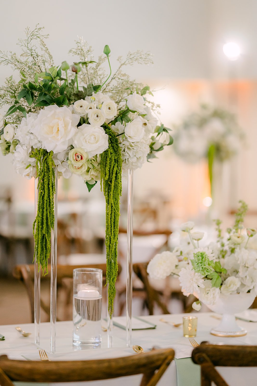 Tall white floral arrangements on the guest tables.