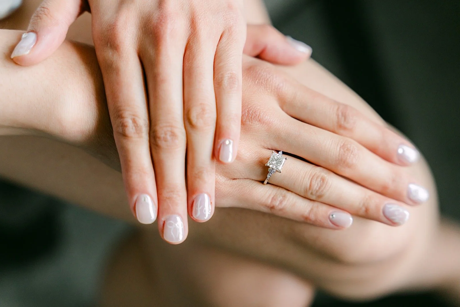 Natalie's hands showing her engagement ring and soft white manicure