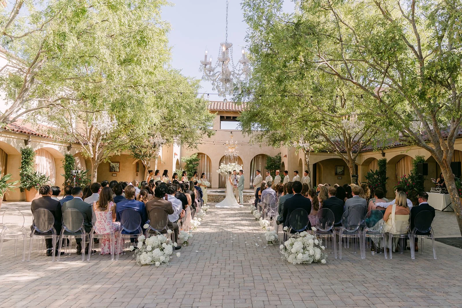 Guests seated under the trees for the Serra Plaza courtyard ceremony