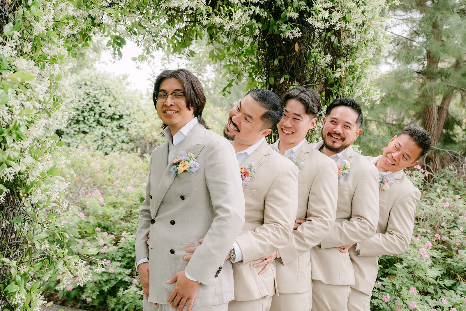 Groomsmen lined up laughing with Mike in the garden