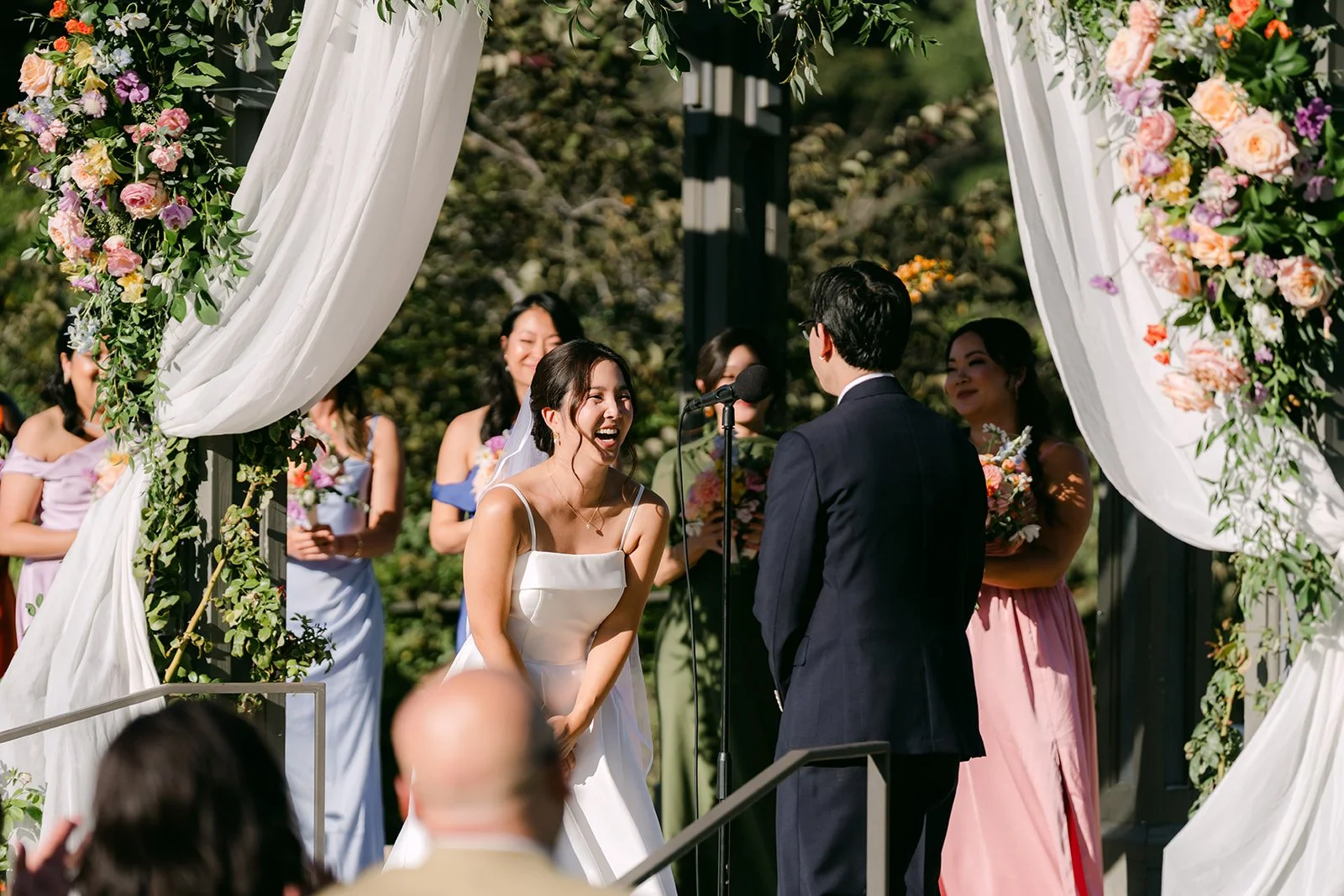Saya and Leroy at the altar framed by white drapery and colorful blooms