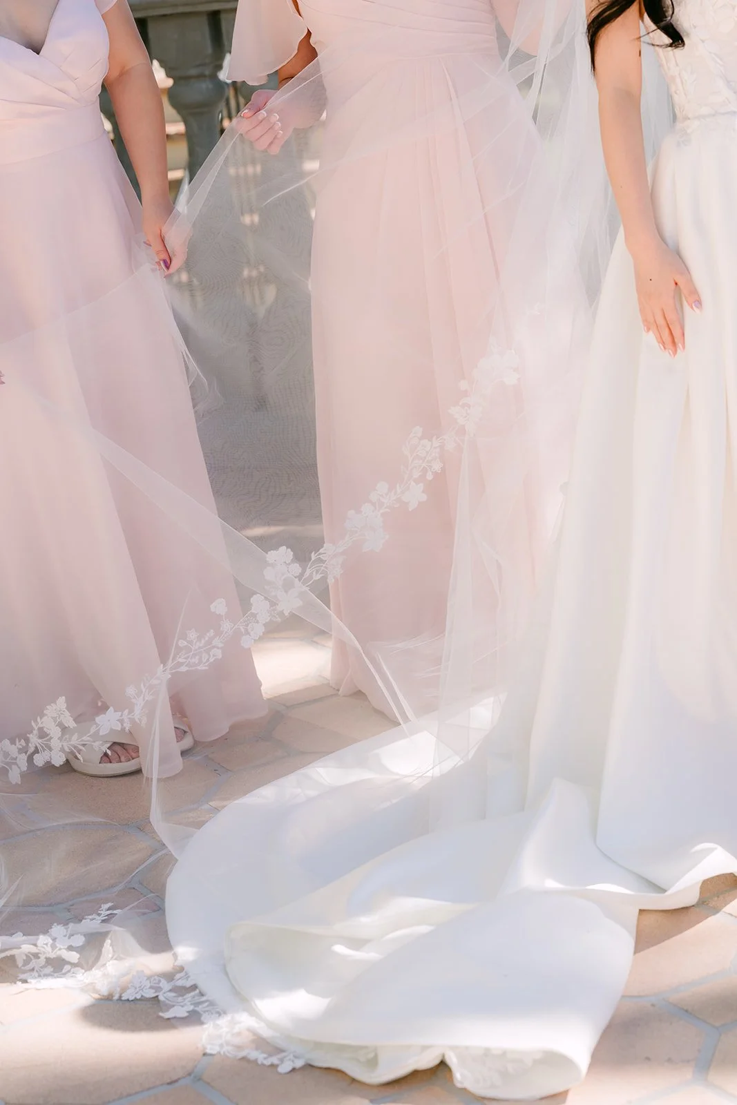 Bridesmaids in blush gowns arranging the bride's train