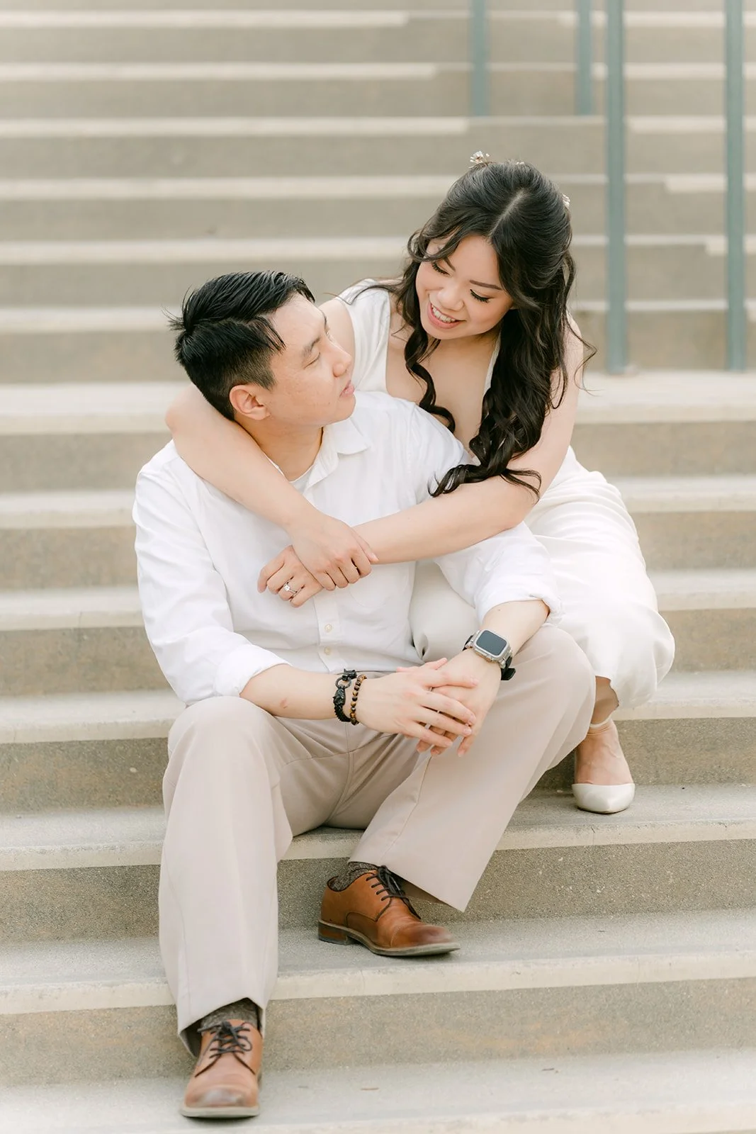 Emily wraps her arms around James as they sit on the steps at Pasadena City Hall.