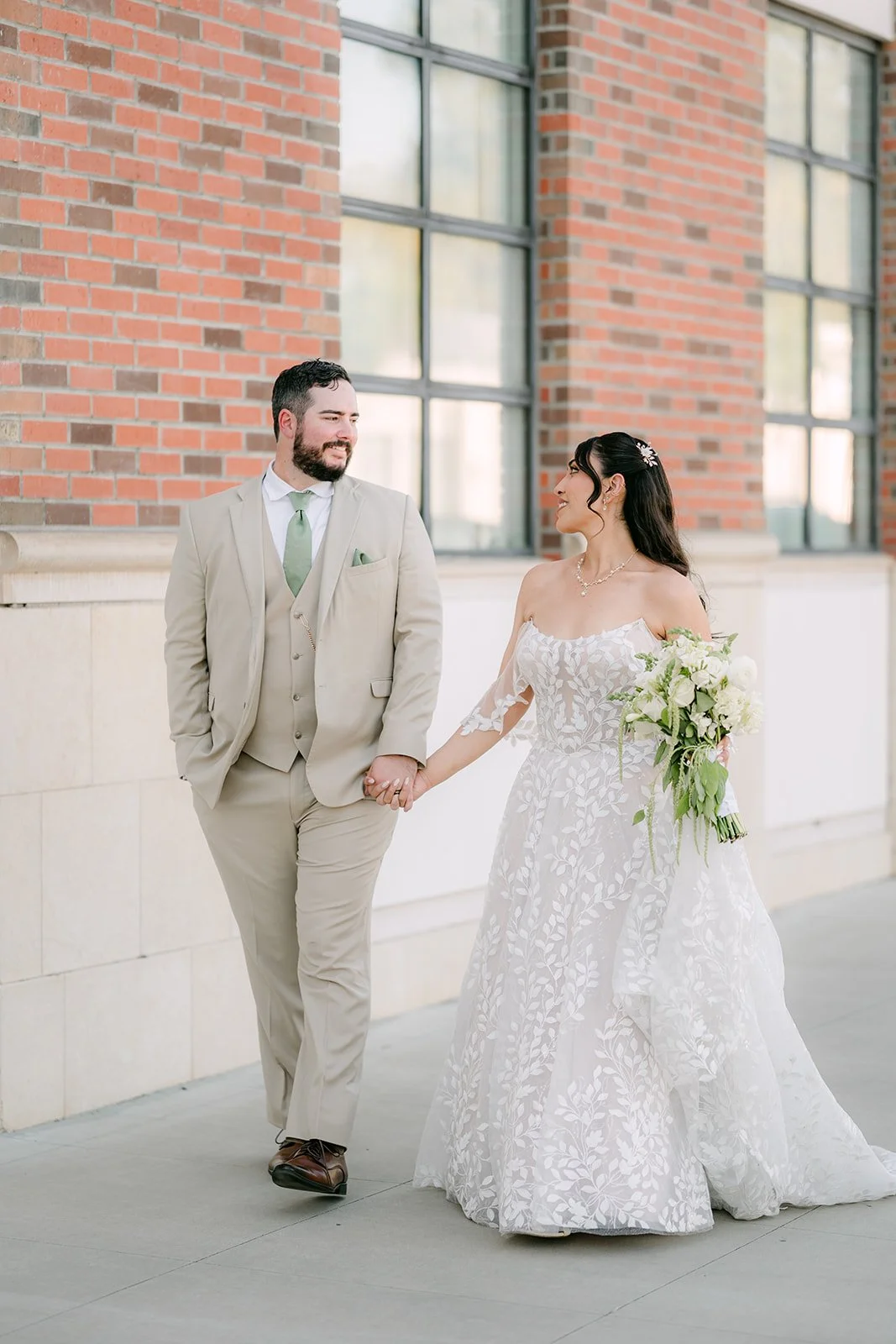 Fernanda and Cody walking together beside a brick building.