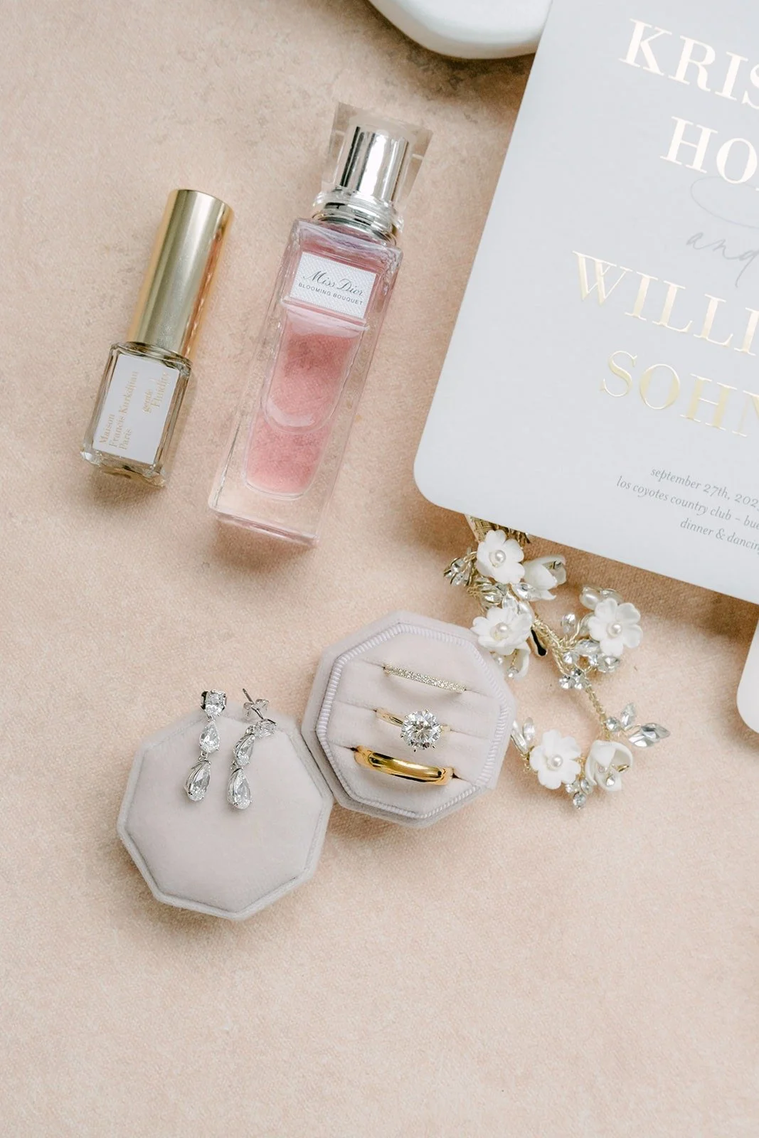 Bridal perfume, earrings and a velvet ring box laid out beside the invitation