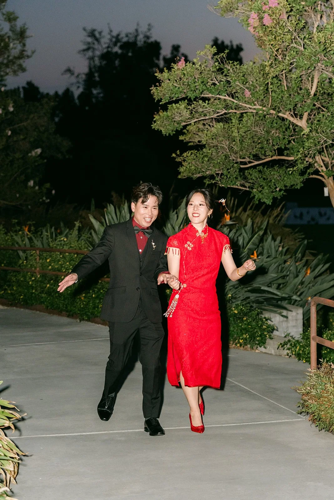 Elaine in a red qipao and Wen in black making their grand entrance at dusk.