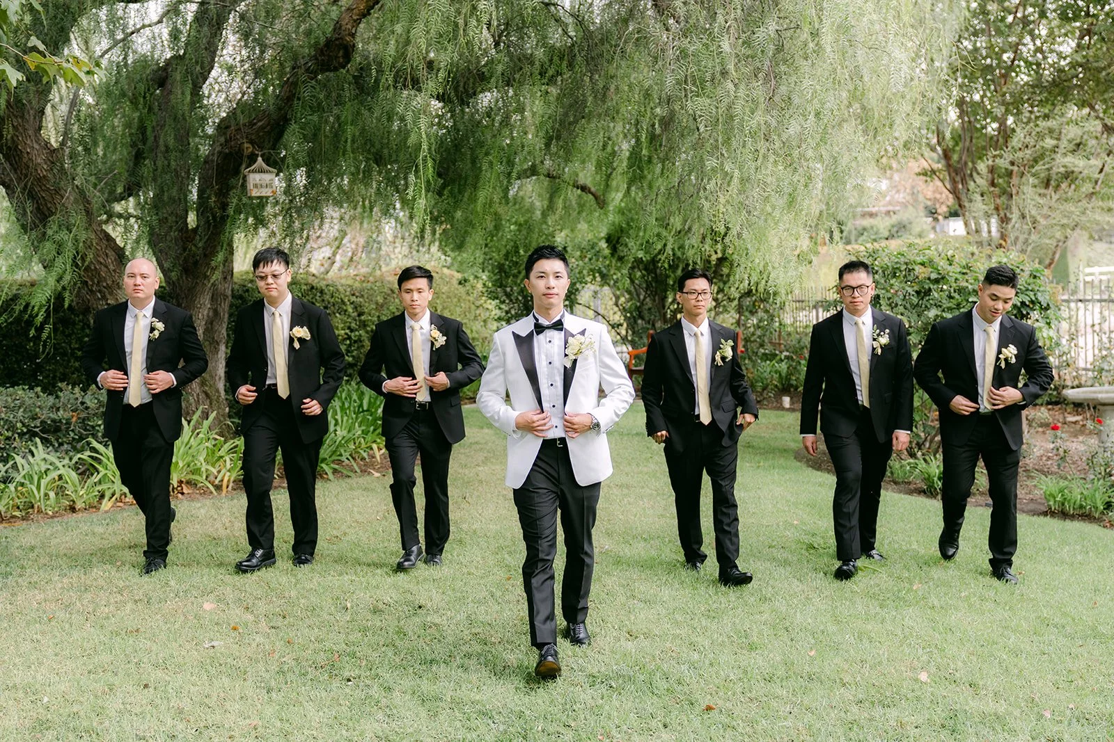 Ryan and his groomsmen walking across the lawn under the willow trees.