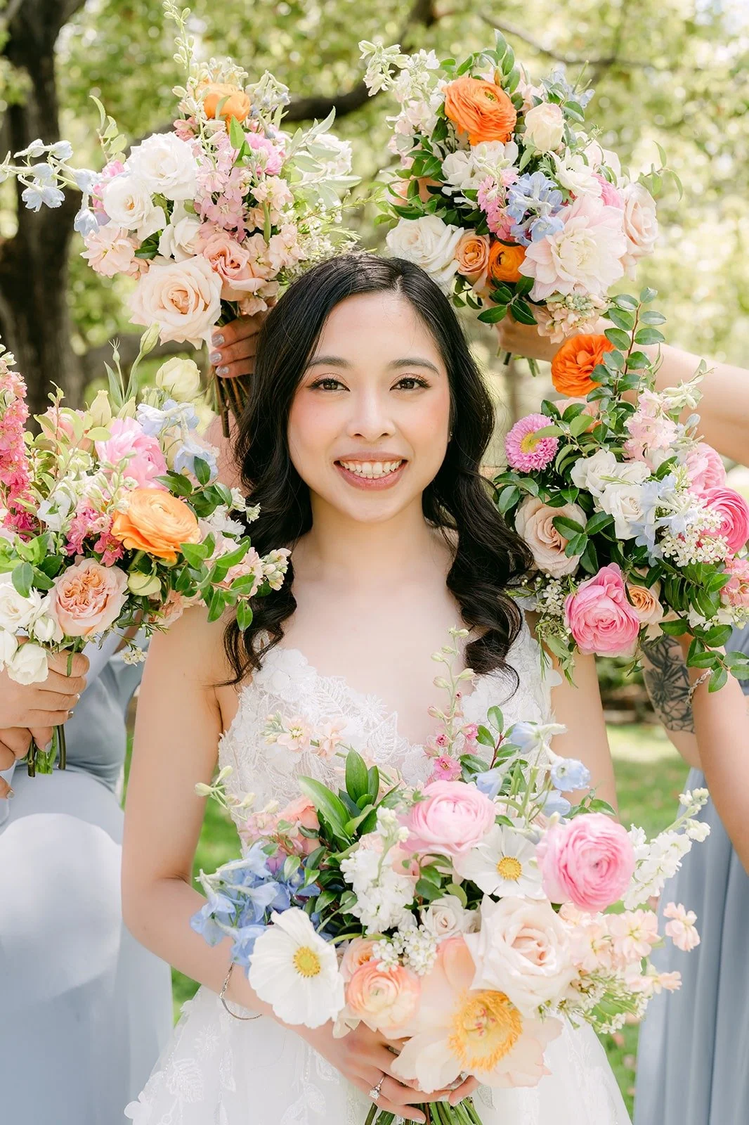 Natalie smiling over her bouquet with the bridesmaids' flowers around her