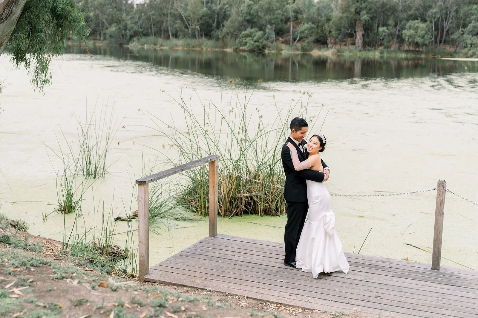 Steven and Jacinda on the dock with the pond and trees around them