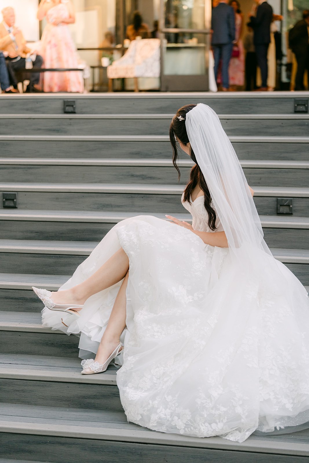 Clarissa seated on stone steps in her gown and veil