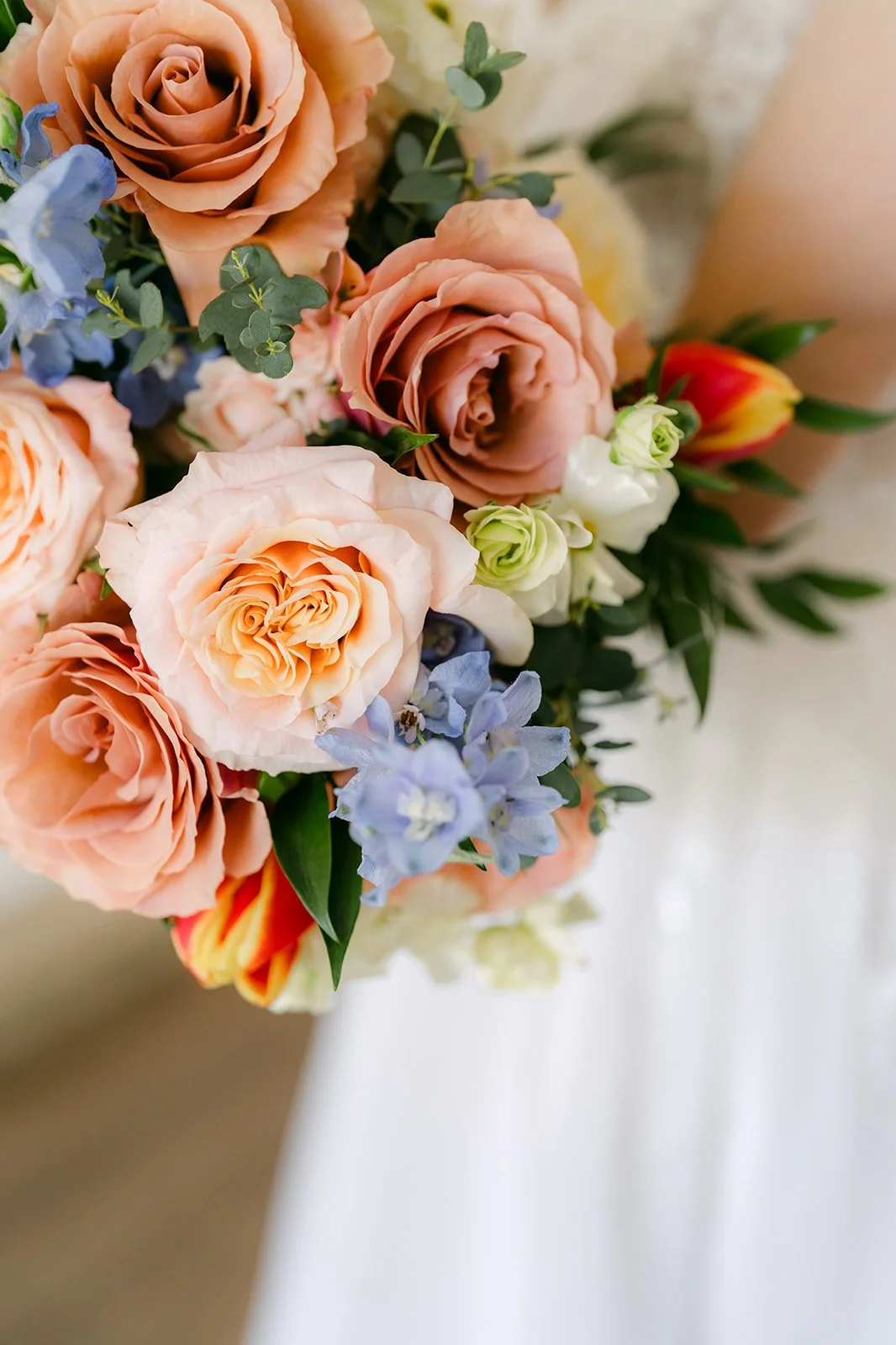 Bridal bouquet of peach roses with dusty blue and terracotta blooms