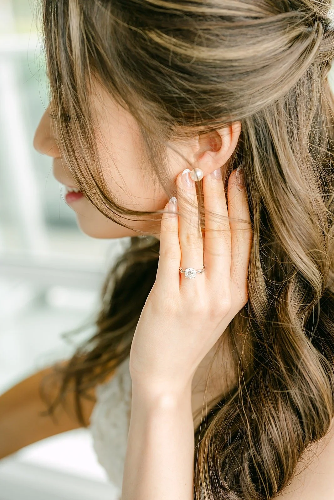 Angela putting on her earrings, her hair falling over one shoulder
