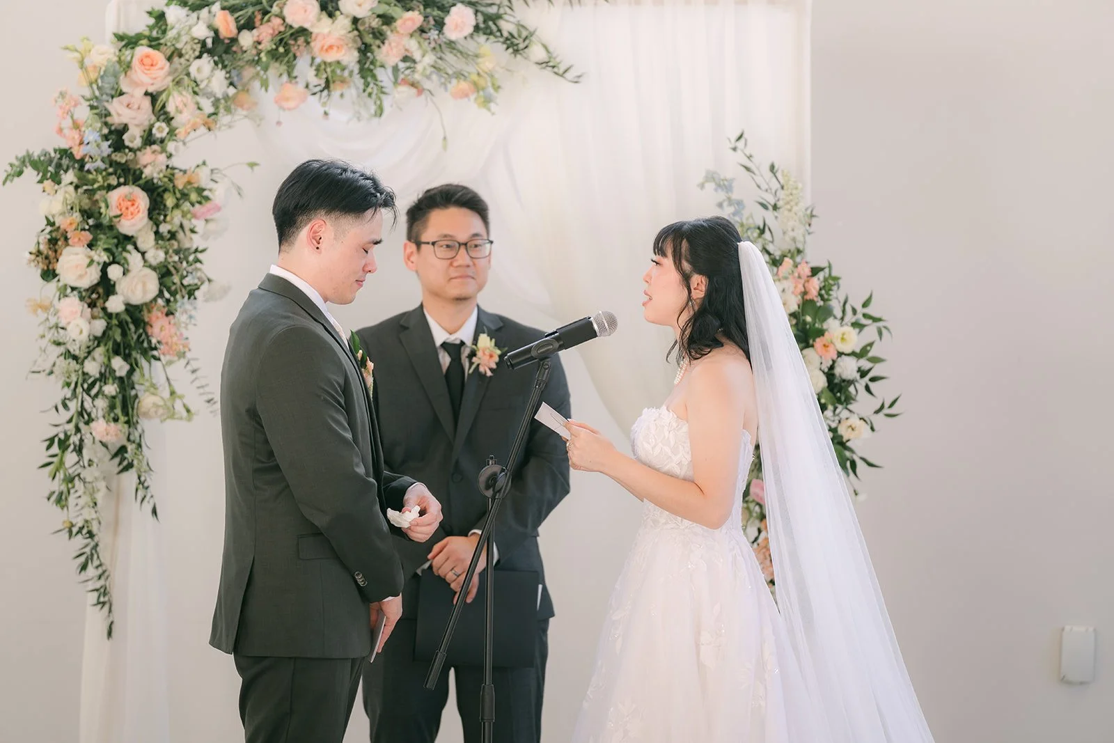 Vivian and Alex at the floral arch with their officiant