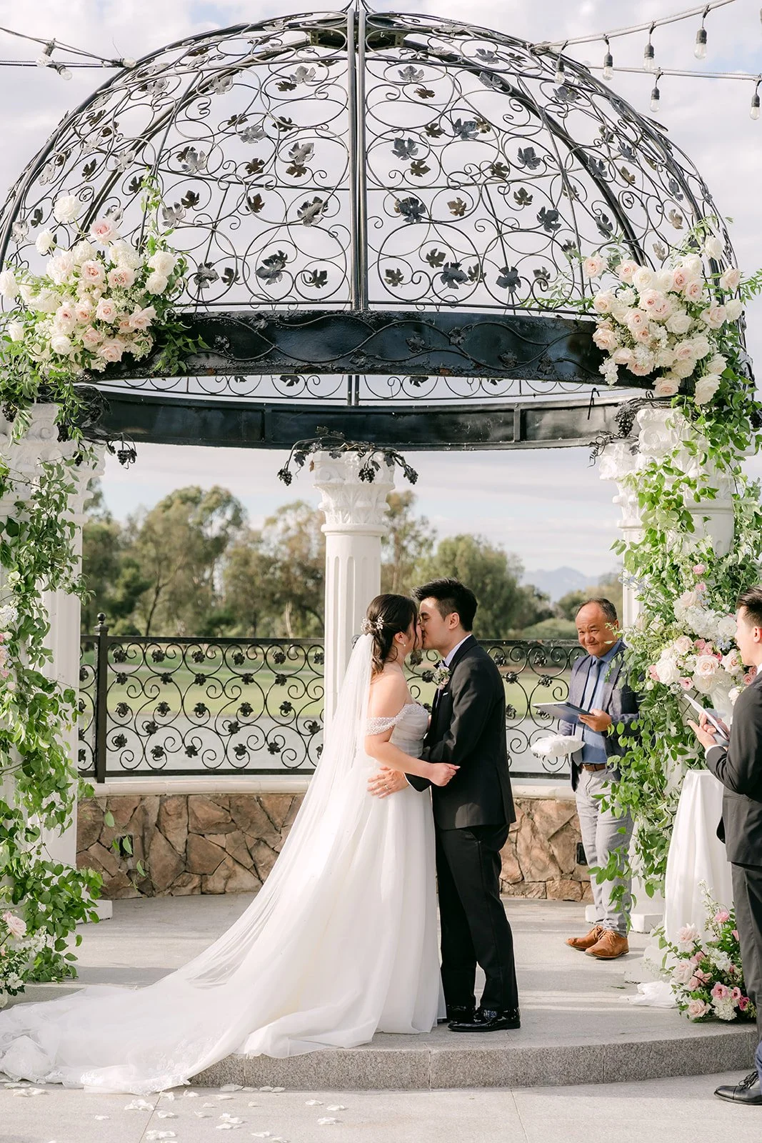 The first kiss beneath the floral gazebo